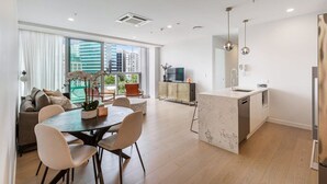 Un appartement moderne doté d’un coin repas, d’une cuisine et de grandes fenêtres offrant une vue sur la ville.