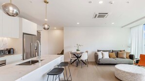 Une cuisine moderne avec un îlot central, un coin repas avec une table ronde et des chaises, un canapé et un pouf rond.