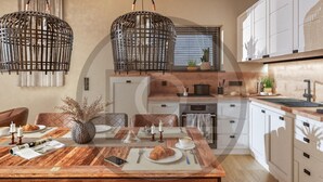 Een moderne keuken met witte kastjes, een houten eettafel en twee hangende rieten manden.