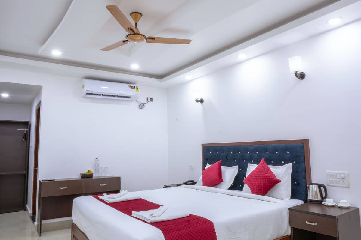 Una habitación de hotel moderna con una cama grande, un ventilador de techo, un equipo de aire acondicionado, una mesita de noche con lámpara y un armario.