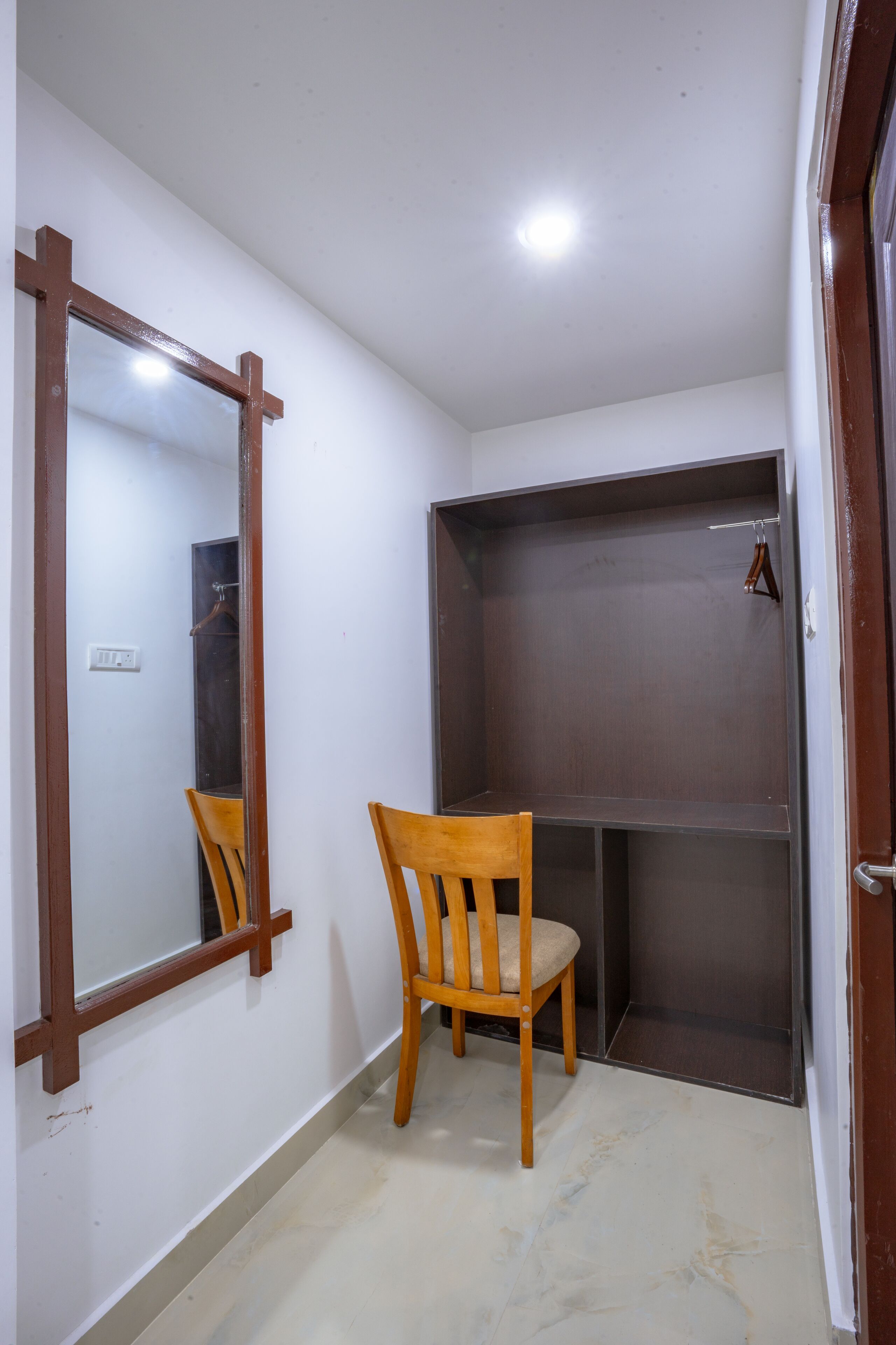 Pequeña habitación cerrada con una silla de madera, un espejo y un armario.