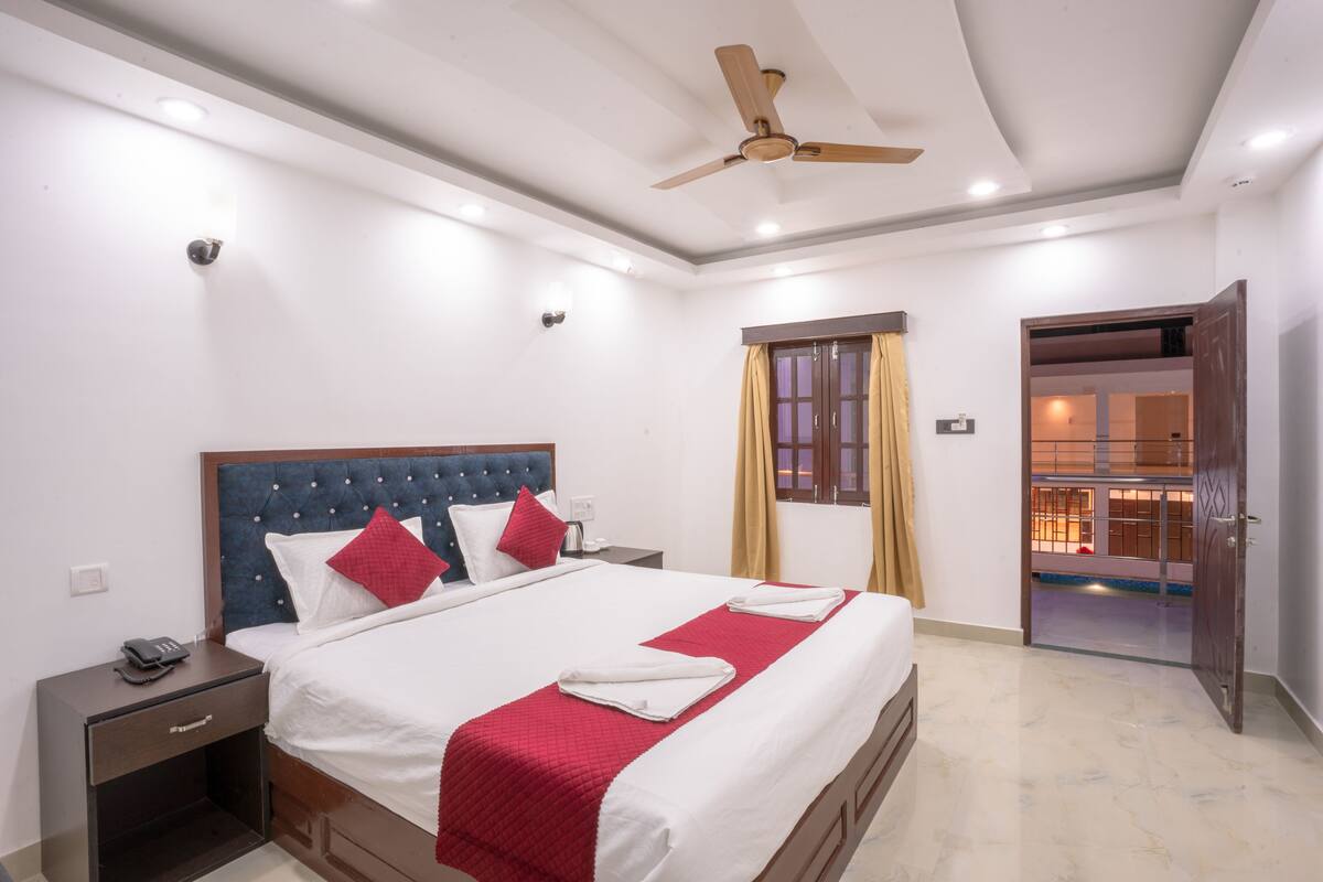 Una habitación de hotel con cama, mesita de noche y ventilador de techo.