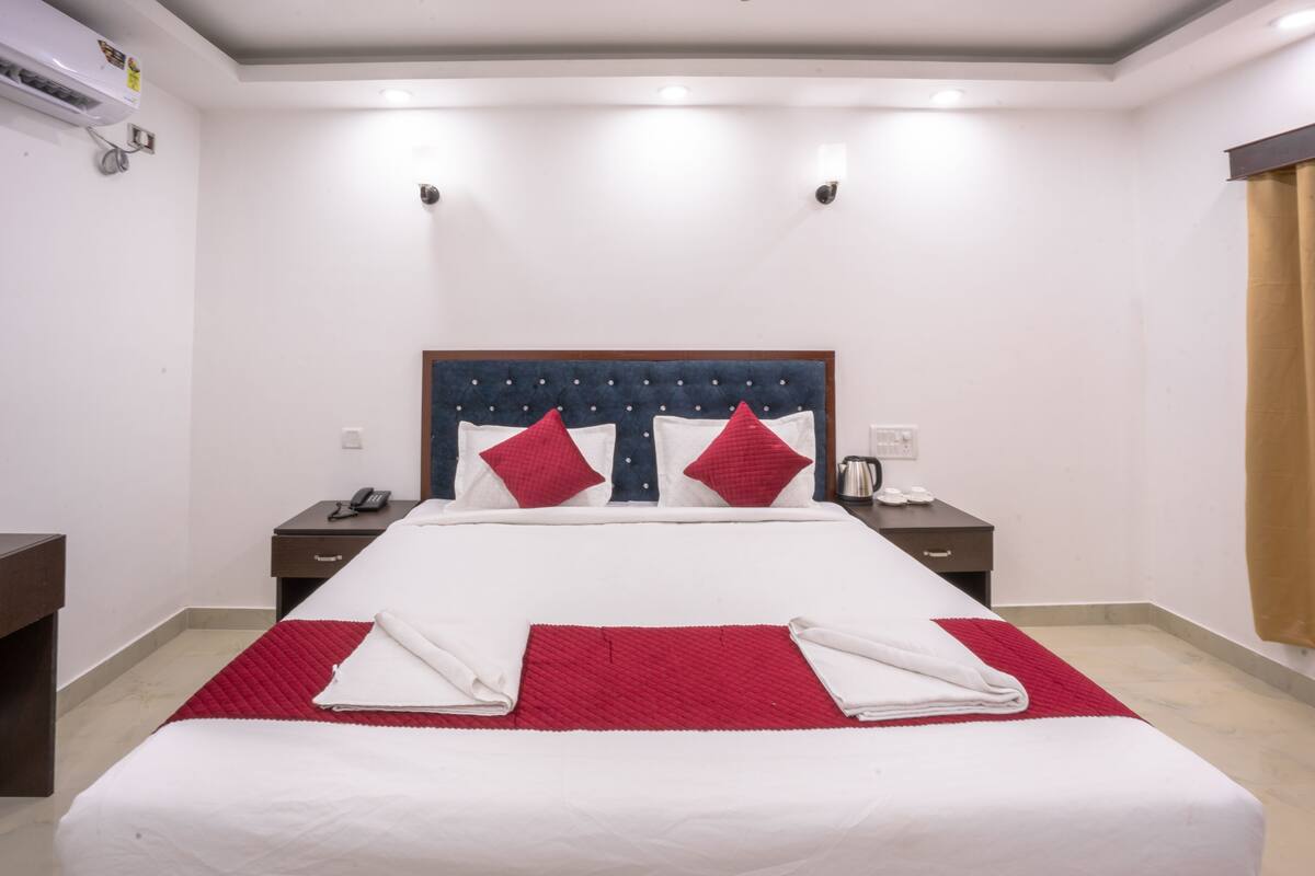 Habitación de hotel con una cama grande, dos mesitas de noche y un aire acondicionado de pared.