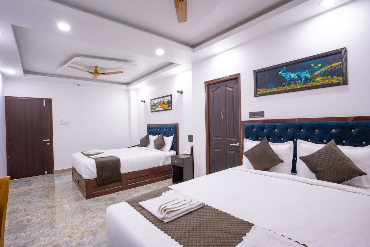 Habitación de hotel con dos camas, un ventilador de techo, un cuadro y una puerta.