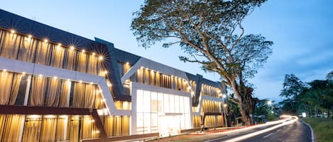 A modern building with large windows and a tree in front.