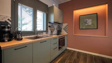 A modern kitchen with a built-in oven, a coffee maker, and a window with blinds.