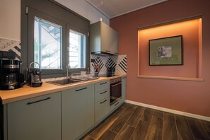 Una cocina moderna con horno integrado, cafetera y ventana con persianas.