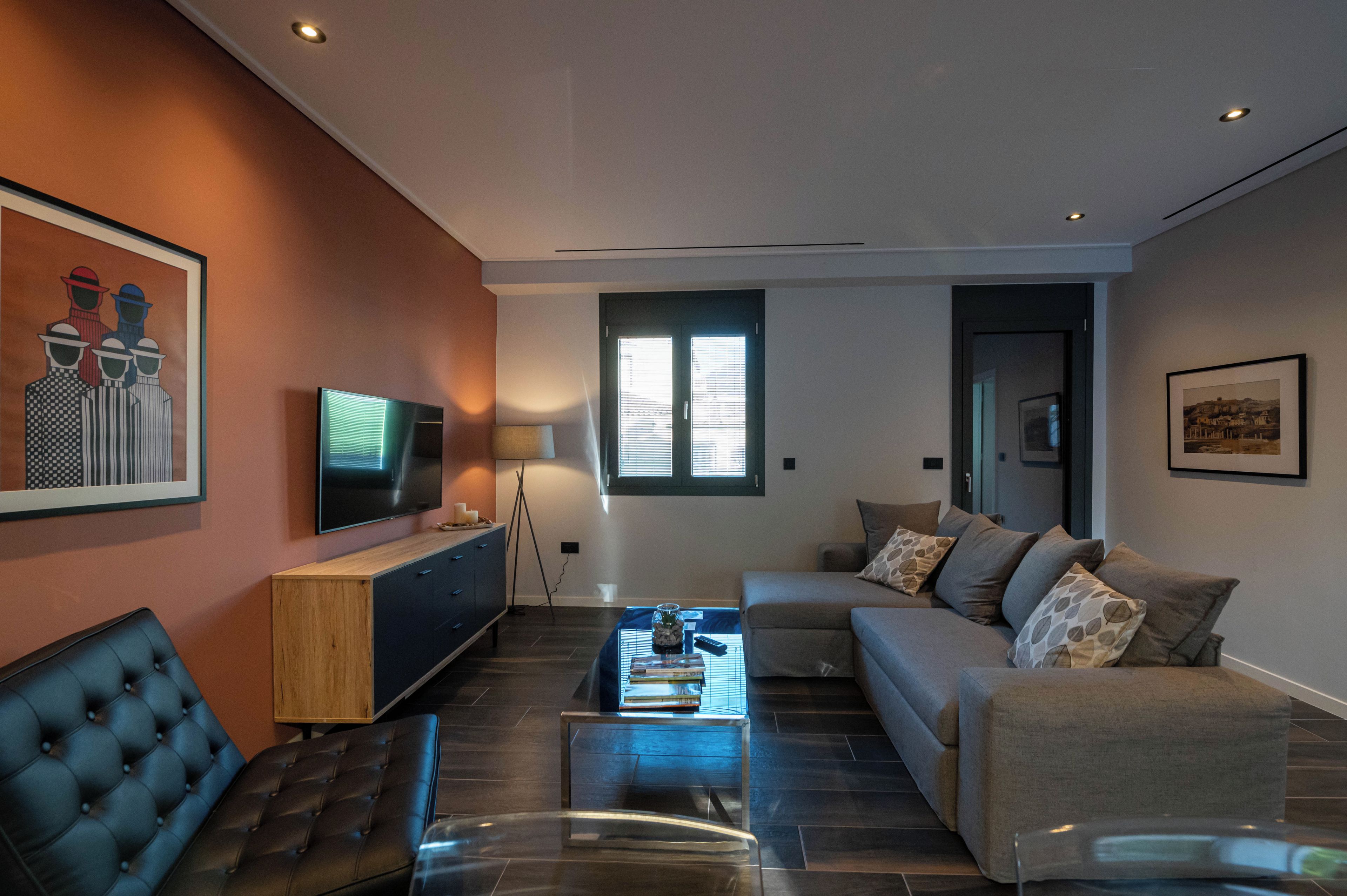 Un salon moderne avec un canapé, une table basse, un téléviseur et des œuvres d’art accrochées aux murs.
