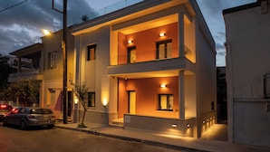 A modern two-story building with a balcony, a sign reading 'Ask Architects,' and a parked car. - Villa Vesta - Kalamata Mediterranean Suites & Villas (Kalamata)