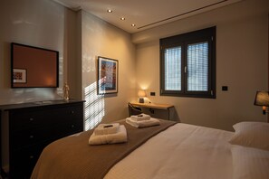 Una habitación de hotel con cama, mesita de noche, lámpara y ventana con persianas.
