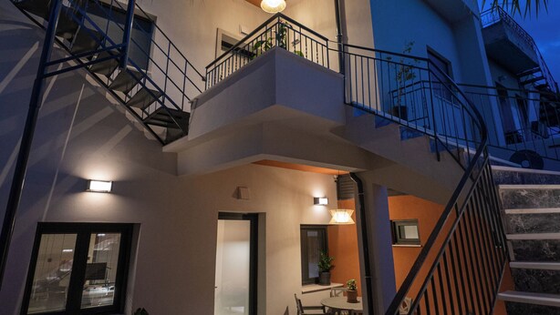 A multi-level residential building with a staircase, balcony, and outdoor seating area.