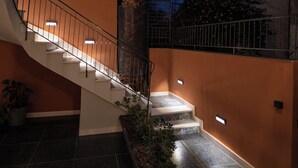 A staircase with a palm tree, surrounded by potted plants, leading to an upper level.