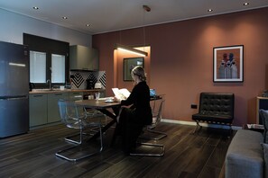 Une cuisine moderne avec un coin repas, un fauteuil en cuir noir et une œuvre d’art encadrée accrochée au mur.
