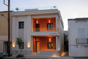A two-story building with a balcony on the upper floor, a sign reading "A&K Architects," and a small tree in front. - Villa Vesta - Kalamata Mediterranean Suites & Villas (Kalamata)
