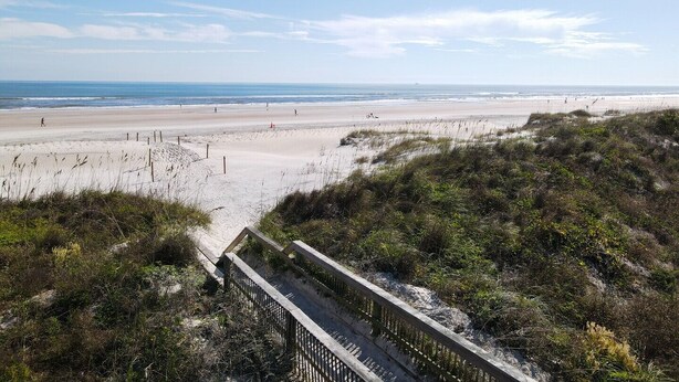 A beach with a wooden boardwalk leading to the shore, surrounded by dunes and vegetation. - Beachside Bliss – Renovated Private Home in Sea Place Community with Resort (St. Augustine)