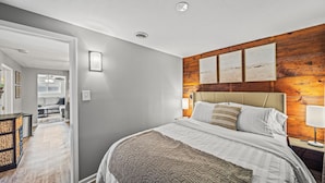 Ein Schlafzimmer mit einem großen Bett, einer Wand mit Holzvertäfelung und einem Flur, der in einen Wohnbereich führt.