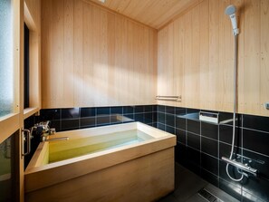 Een moderne badkamer met een houten wastafelmeubel, een badkuip en een douche.