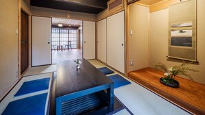 Um quarto japonês tradicional com tatames, uma mesa baixa, portas deslizantes e vista para um deck de madeira.