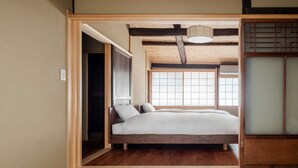 Quarto em estilo japonês tradicional, com tatames, cama de madeira baixa, portas deslizantes e um separador shoji.