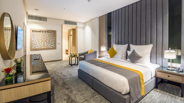 A modern hotel room with a large bed, a desk, a chair, and a TV. - Erfad Hotel-Riyadh (Riyadh)