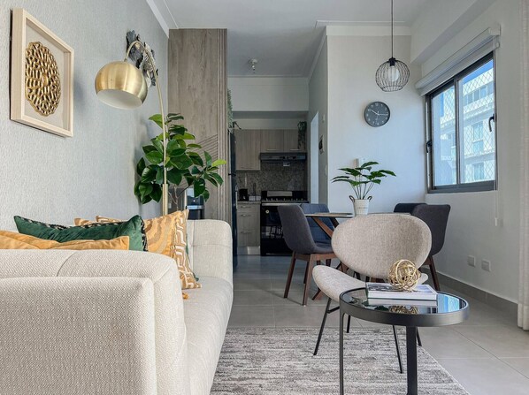 A modern living room with a sofa, chairs, a coffee table, and a dining area with chairs and a table.