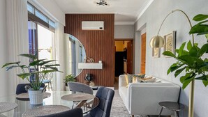 Un salon moderne comprenant un canapé, des fauteuils, une table basse et un coin repas avec une table et des chaises.