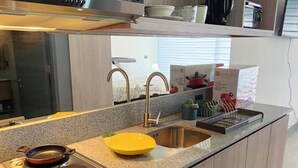 Une cuisine moderne équipée d’une cuisinière intégrée, d’un évier et d’un plan de travail agrémenté de divers ustensiles.