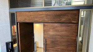 Un intérieur moderne avec une armoire en bois, une porte en verre et un plafond doté de luminaires linéaires.