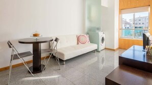 Un salon moderne avec un canapé, une table ronde et un lave-linge.