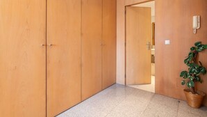 Un couloir avec des portes en bois, un sol carrelé et une plante en pot.