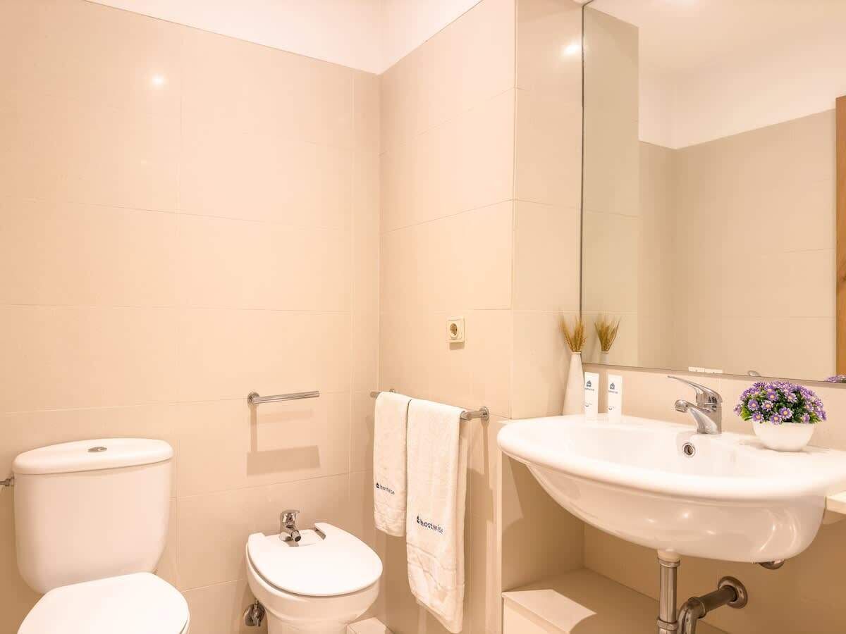 A bathroom with a toilet, bidet, sink, and a mirror.