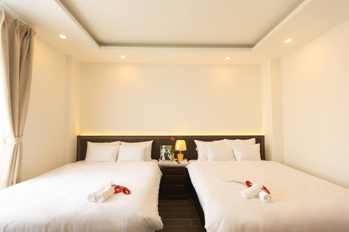 Habitación de hotel con dos camas, una mesita de noche con lámpara y una escalera que conduce a un nivel superior.