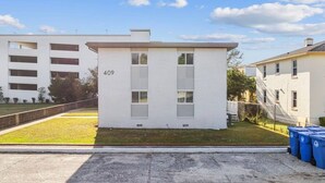 A small, white brick building with the number 409, located in a grassy area with a paved path leading to it.