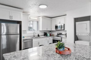 A modern kitchen with stainless steel appliances, white cabinetry, and a granite countertop. - Azul Condos 4 | 2 Bedroom, Near Ocean, Kitchen (Myrtle Beach)