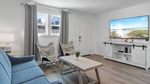 A modern living room with a sofa, a dining table, and a TV.