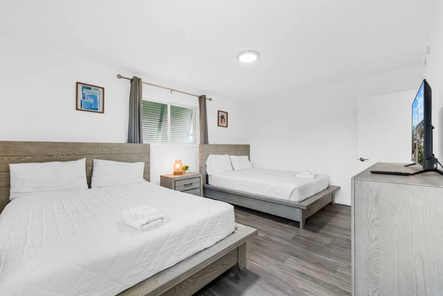 A hotel room with two beds, a television, and a small table with a lamp.