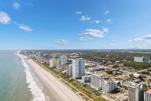 Un paisaje urbano costero con una playa, edificios altos y cielo despejado.