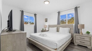 Ein Hotelzimmer mit einem Bett, Nachttischen, einem Fernseher und Fenstern mit Vorhängen.