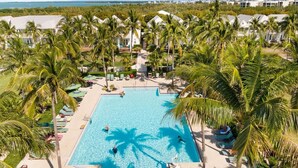 Un resort con una amplia piscina rodeada de palmeras y sillas de playa.