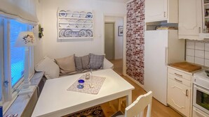 Una cocina compacta con comedor, armarios blancos y una pared de ladrillo decorativa.
