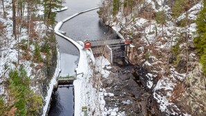 Una presa con un sistema de esclusas, rodeada de árboles cubiertos de nieve y terreno rocoso.
