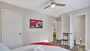Camera d'albergo con un letto, una ventola a soffitto, una TV a parete e un pavimento in legno.