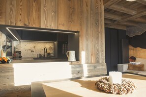 A modern interior with a wooden accent wall, a kitchen area, and a seating area with a decorative pine cone arrangement.