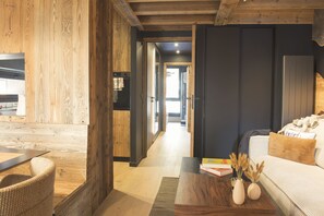 A modern interior with wooden walls, a sofa, a coffee table, and a dining area.