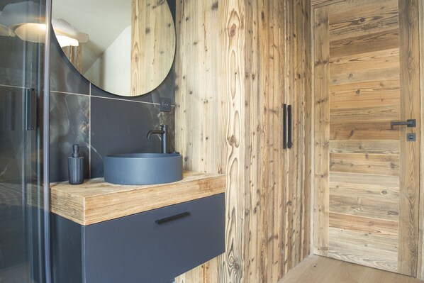 Un bagno con un mobile contenitore in legno, uno specchio rotondo e un lavandino moderno.
