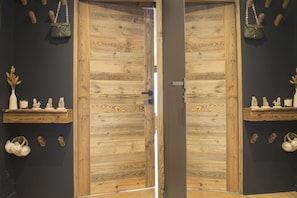 A wooden door with a modern handle, flanked by two wooden shelves with decorative items.