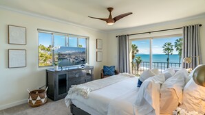 Une chambre avec un grand lit, un bureau et une vue sur l’océan.