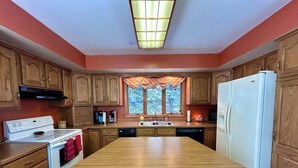 Una cocina con armarios de madera, una estufa blanca, un refrigerador blanco y una isla grande.