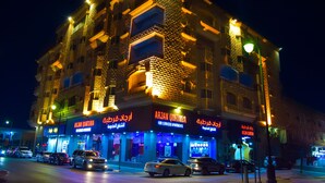 A multi-story building with illuminated signage for 'ARJAN QURTAUBA' and 'ARJAN QURTAUBA FOR SERVICED APARTMENTS'. - ARJAN QURTUBA SERVICED APARTMENTS (Al Khobar)