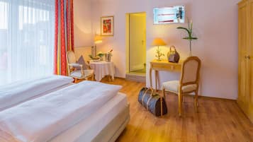Una habitación de hotel con cama, escritorio, silla, televisión y armario.